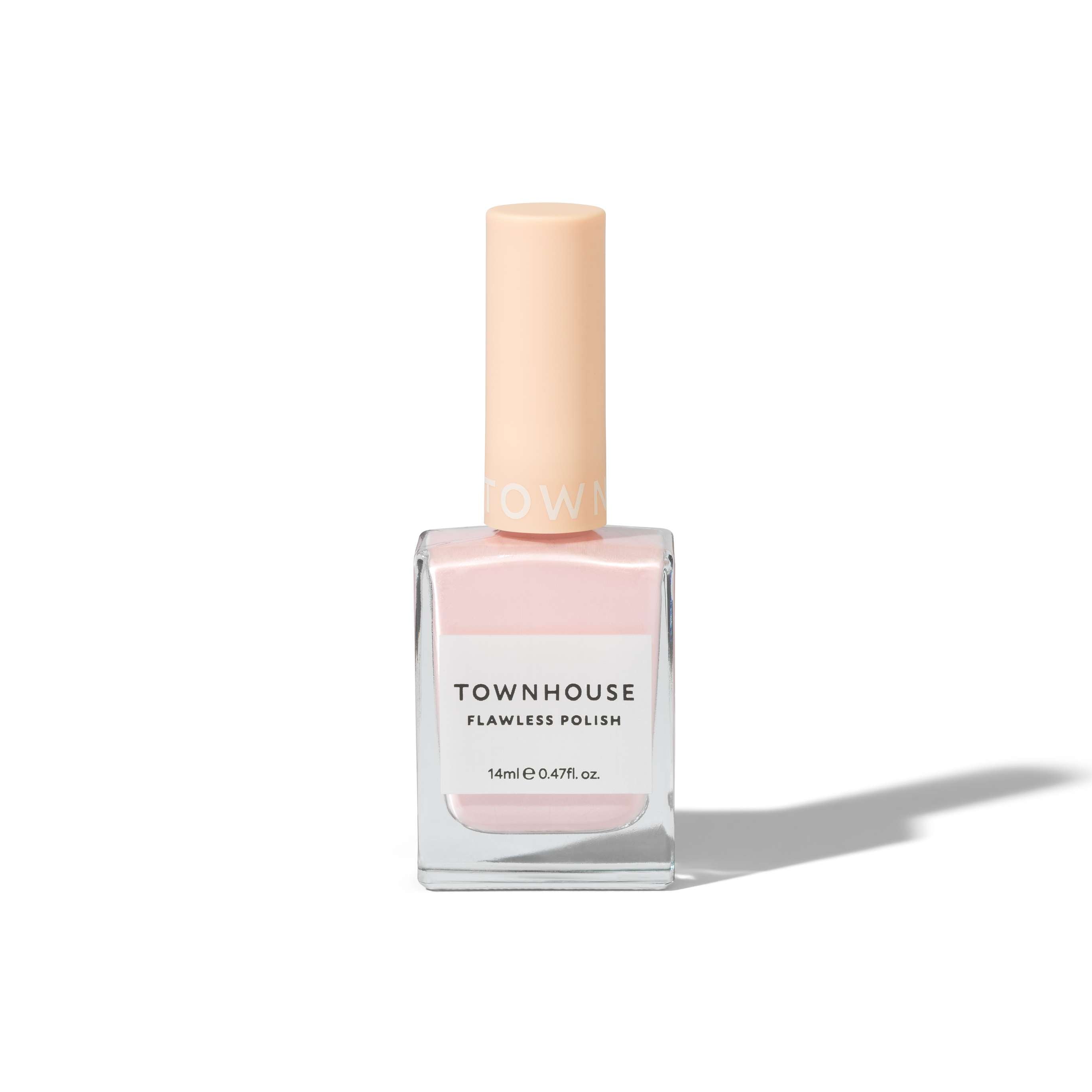 A bottle of TH - Glazed Milkshake Polish 14ml in a soft beige-pink hue, featuring a square clear glass base and a pale peach cap, is standing on a white background with a faint shadow.