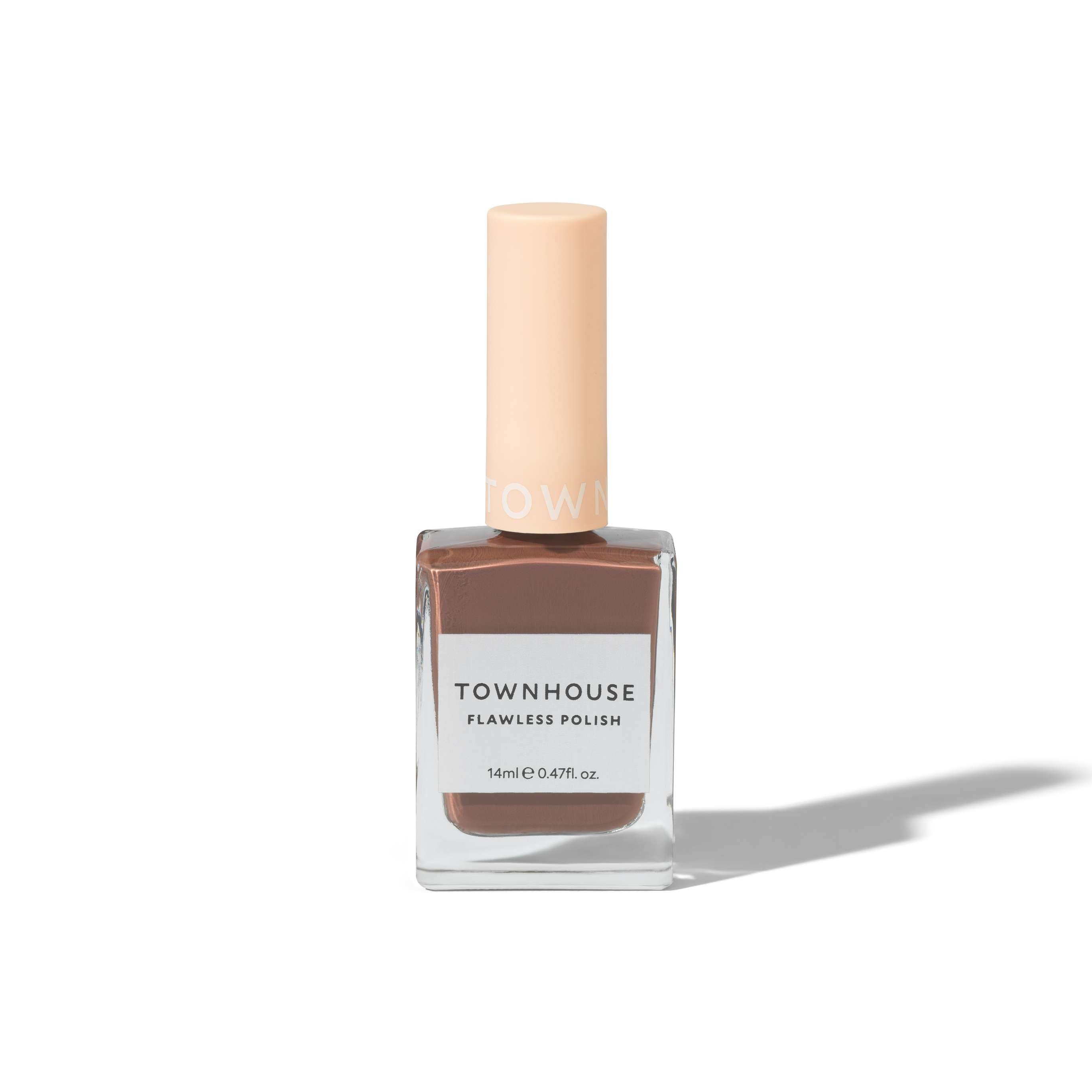 A bottle of TH - Hot Chocolate Polish 14ml, featuring a light brown nail lacquer housed in a square glass bottle with a pale beige cap, is set against a white background with a faint shadow—an elegant choice that pairs beautifully with rich shades like molten dark brown nail polish or the soothing touch of nourishing cuticle oil.