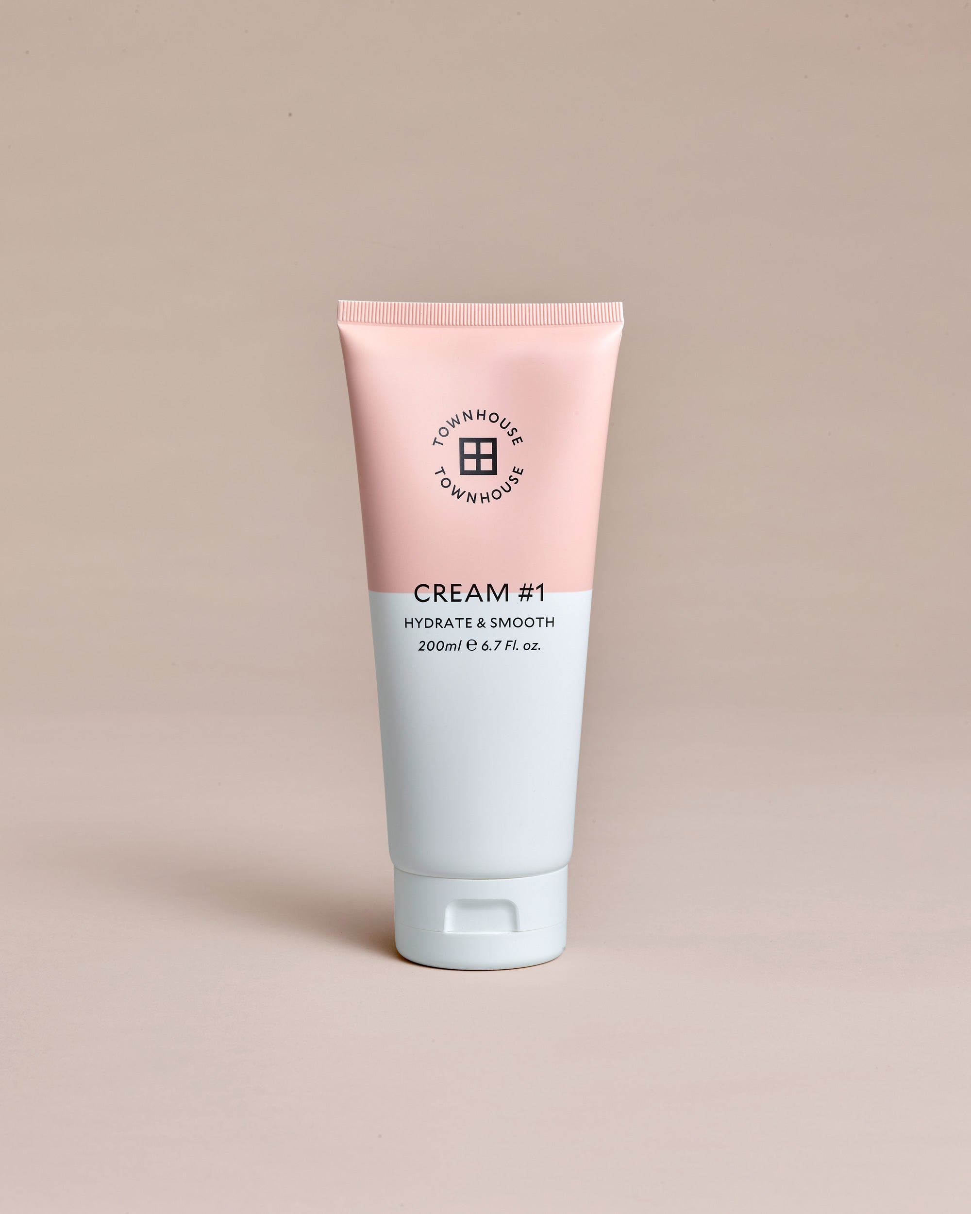 A pink and white tube labeled “Townhouse Cream#1 200ml” stands upright on a beige background, highlighting a hydrating cream that exemplifies the brand’s dedication to cruelty-free skincare.
